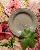 Decorative Wedgwood drabware plate with leaf design on a floral fabric background