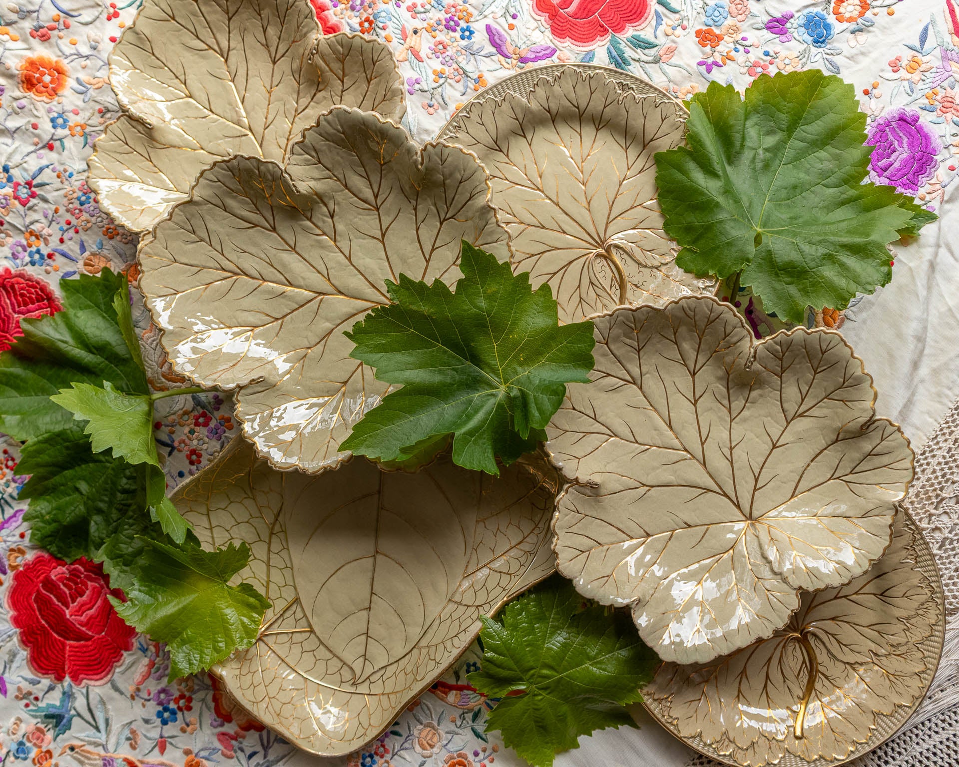 Decorative leaf-shaped Wedgwood plates with green leaves and flowers on a patterned background