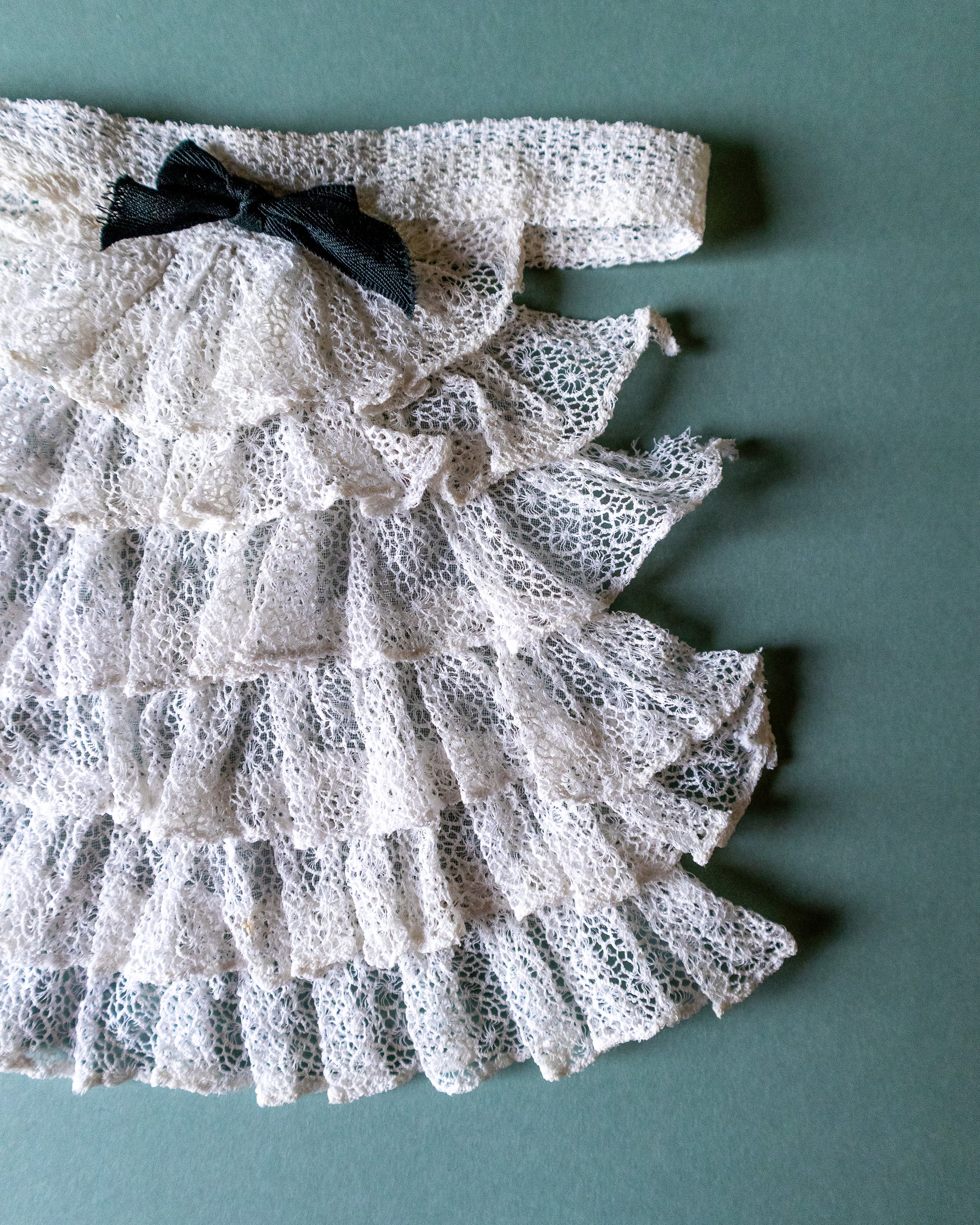 Lace jabot with a bow on a teal background