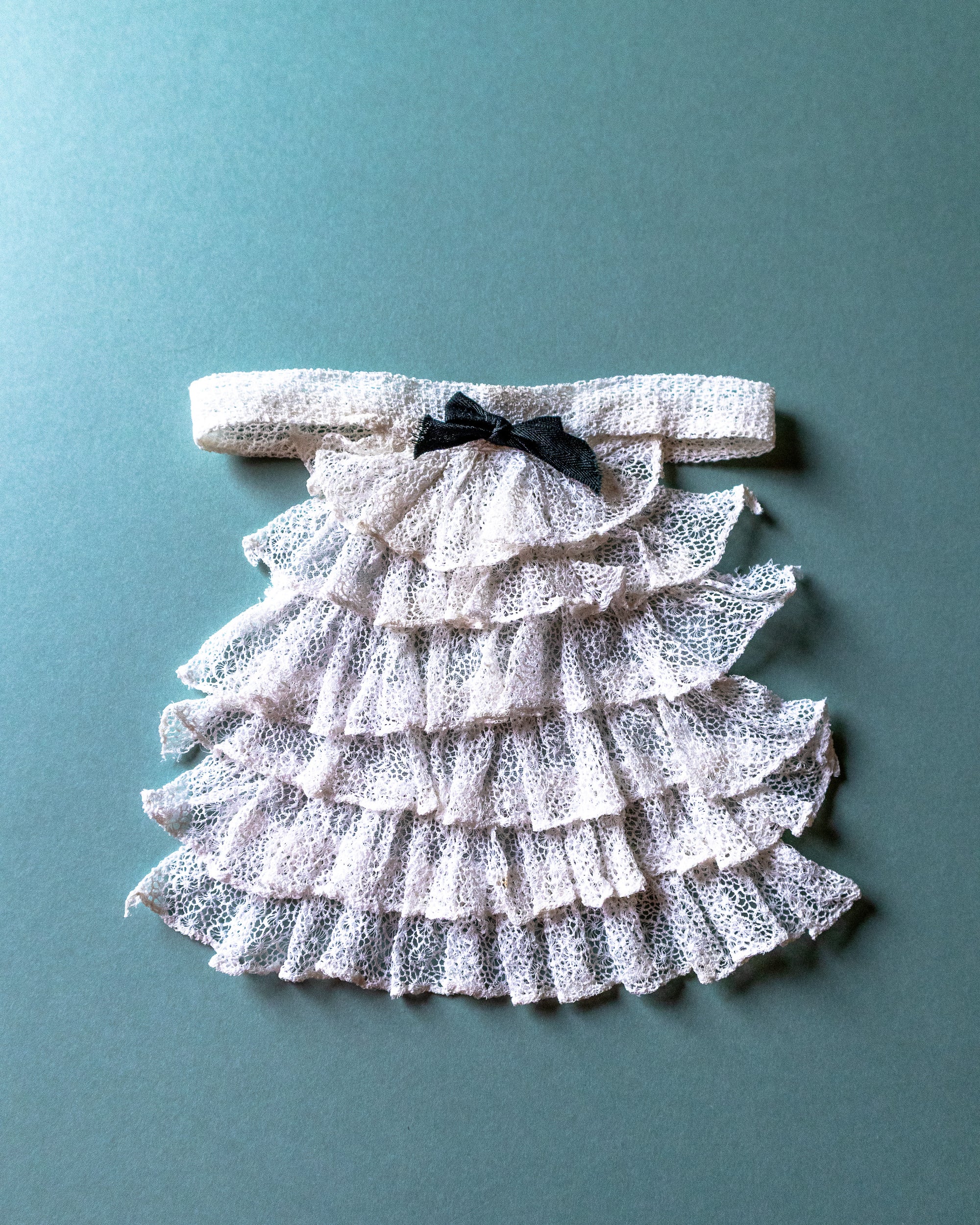 Lace jabot with a bow on a teal background