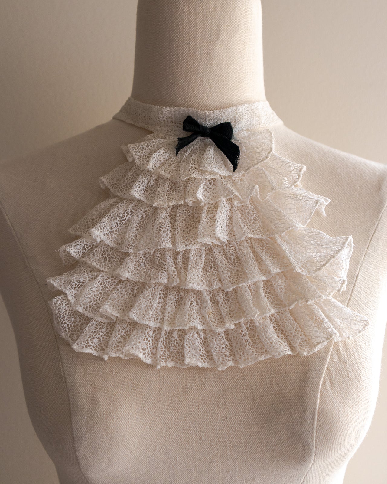 White lace jabot with a black bow on a mannequin