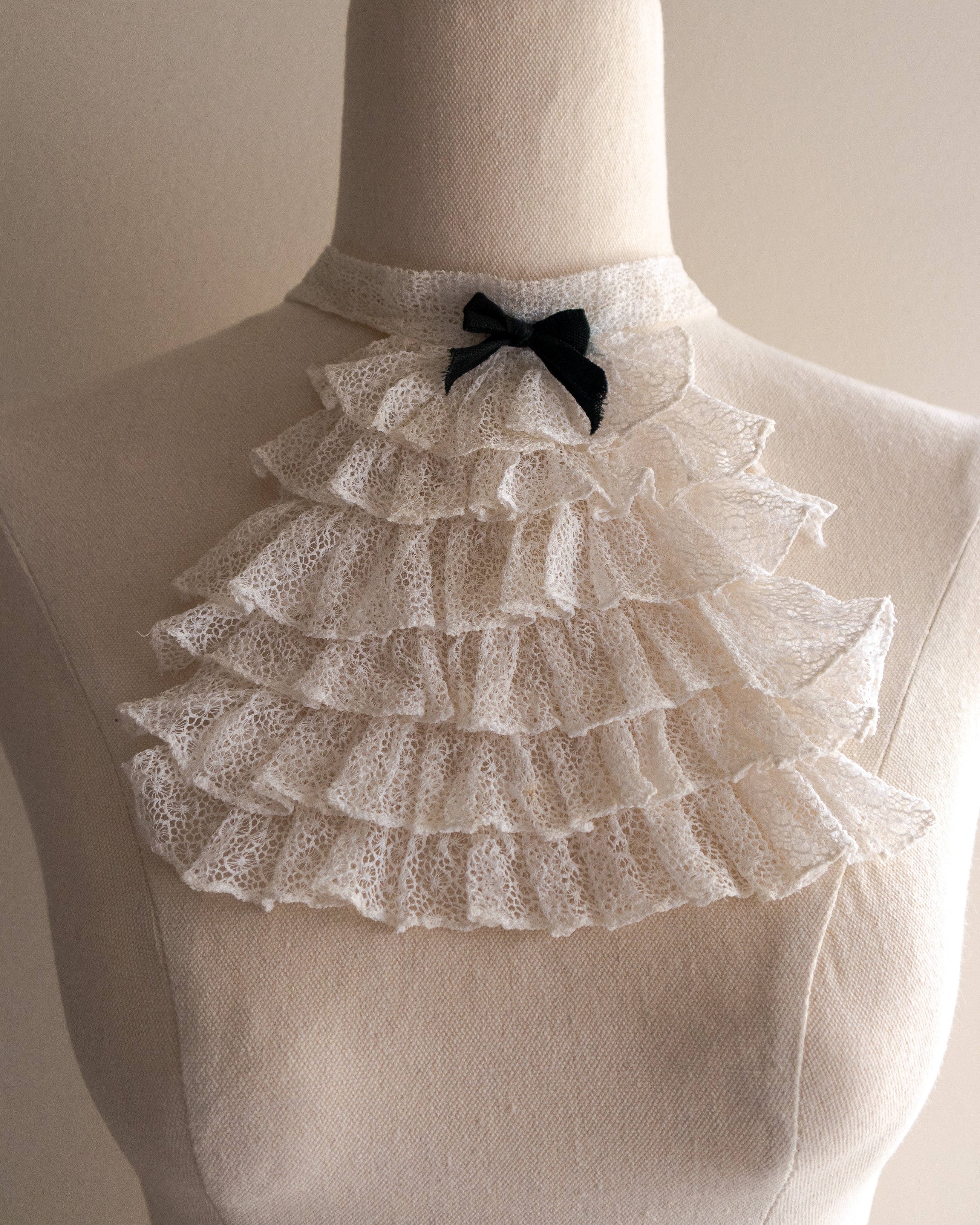 White lace jabot with a black bow on a mannequin