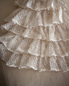 Close-up of lace fabric with ruffled edges on a neutral background
