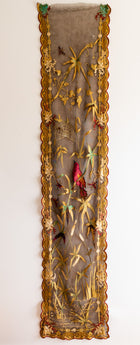 Decorative panel with gold frame and embroidered details on a white background
