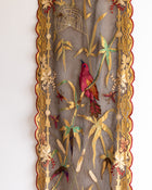 Decorative panel with embroidered bird, flowers, and spider web on a plain background