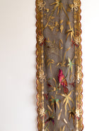 Decorative fabric panel with embroidered birds and flowers in a gold frame on a white background