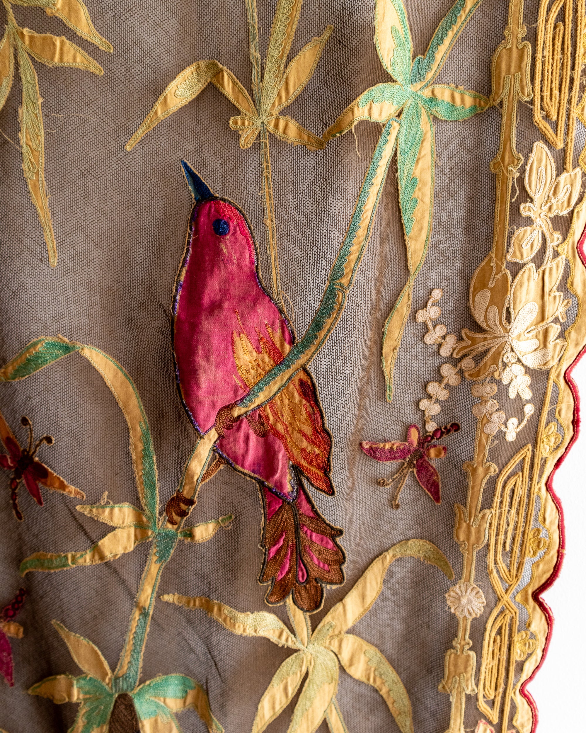 Embroidered fabric with a red bird and gold leaves on a brown background