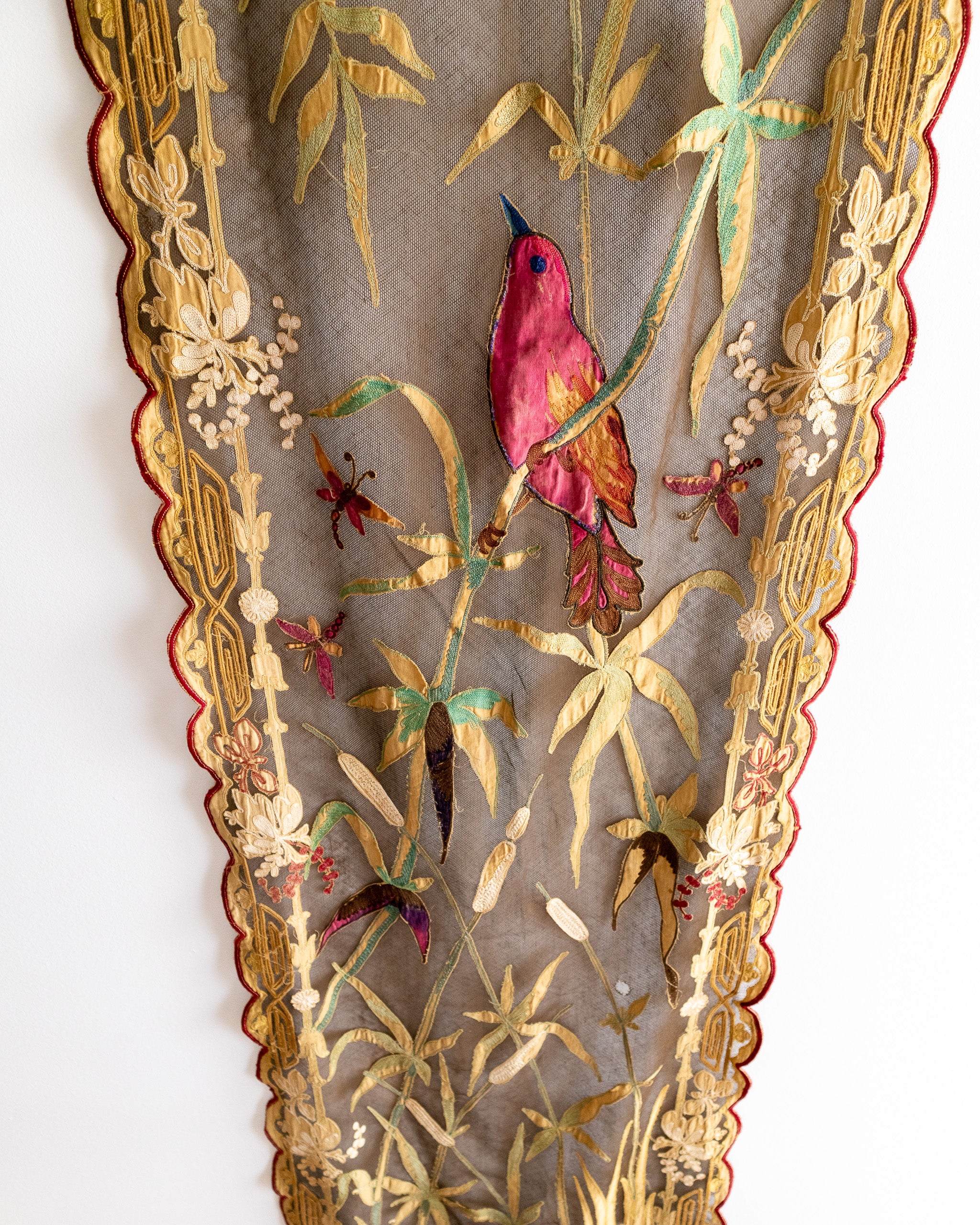 Decorative panel with embroidered red bird and floral patterns on a textured background