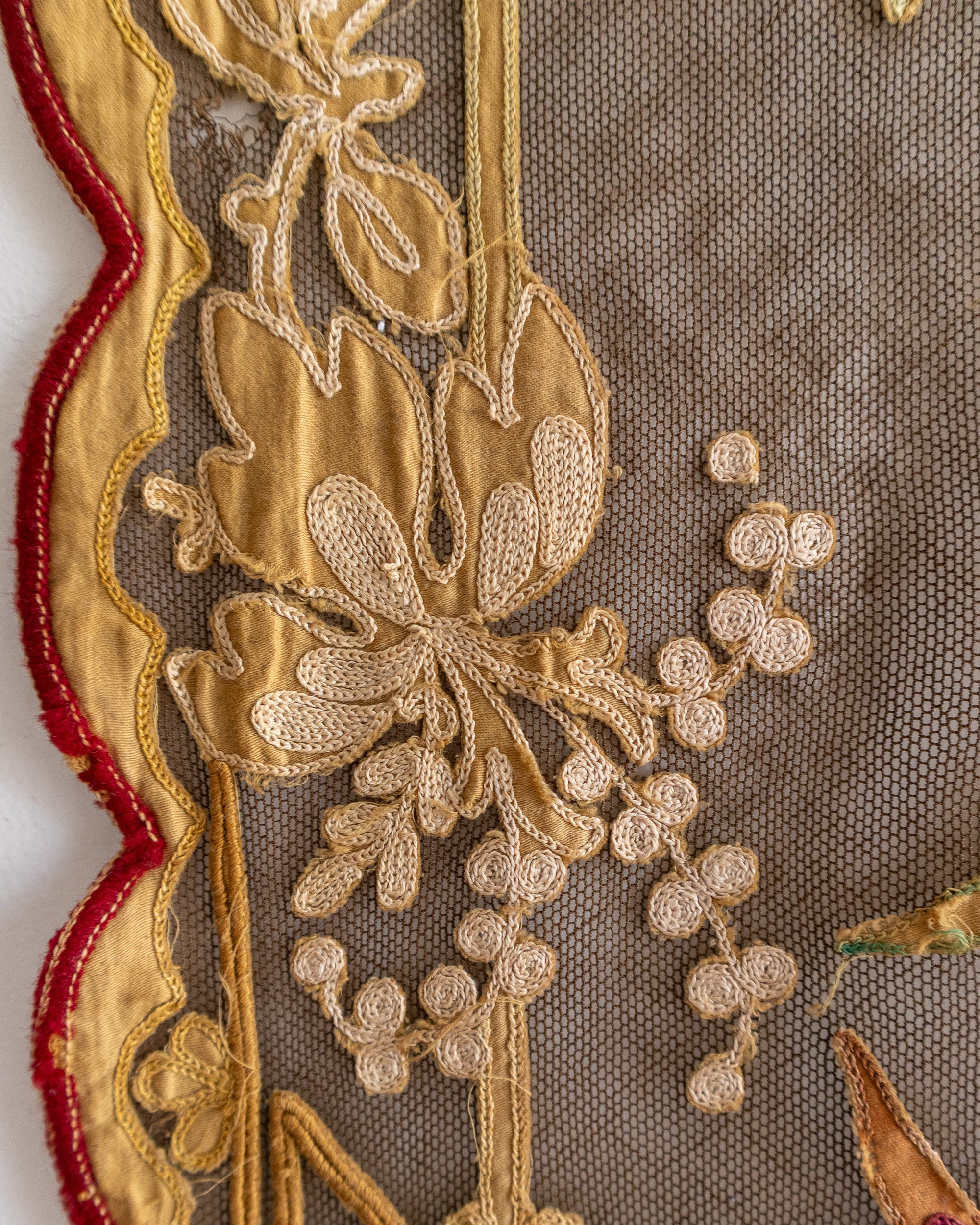 Close-up of gold floral embroidery on a fabric with red border