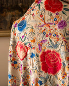 Close-up of a scarf with intricate floral and bird embroidery.