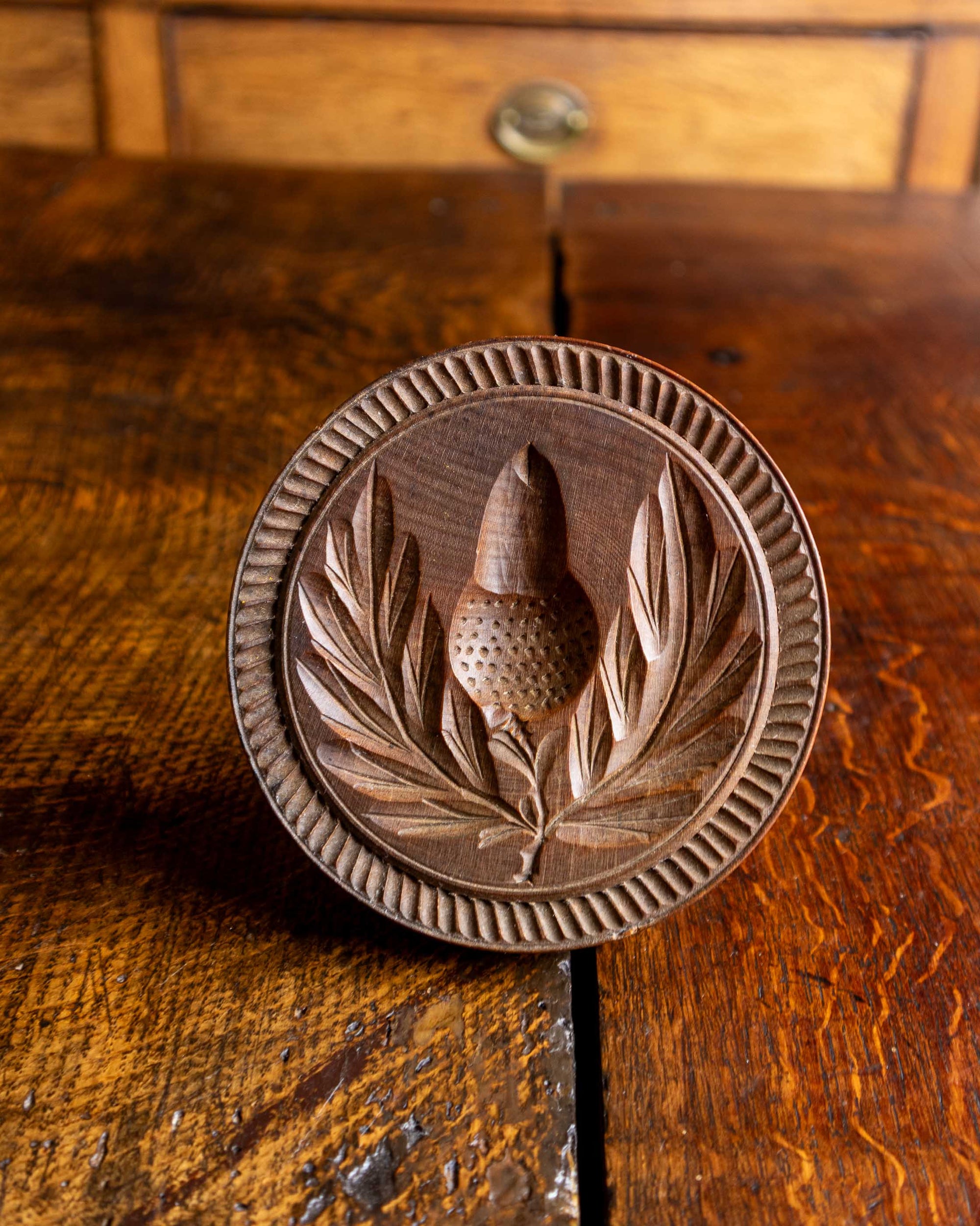 Wooden butter print with acorn design on a wooden surface