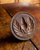Wooden butter stamp with leaf and acorn design on a wooden surface