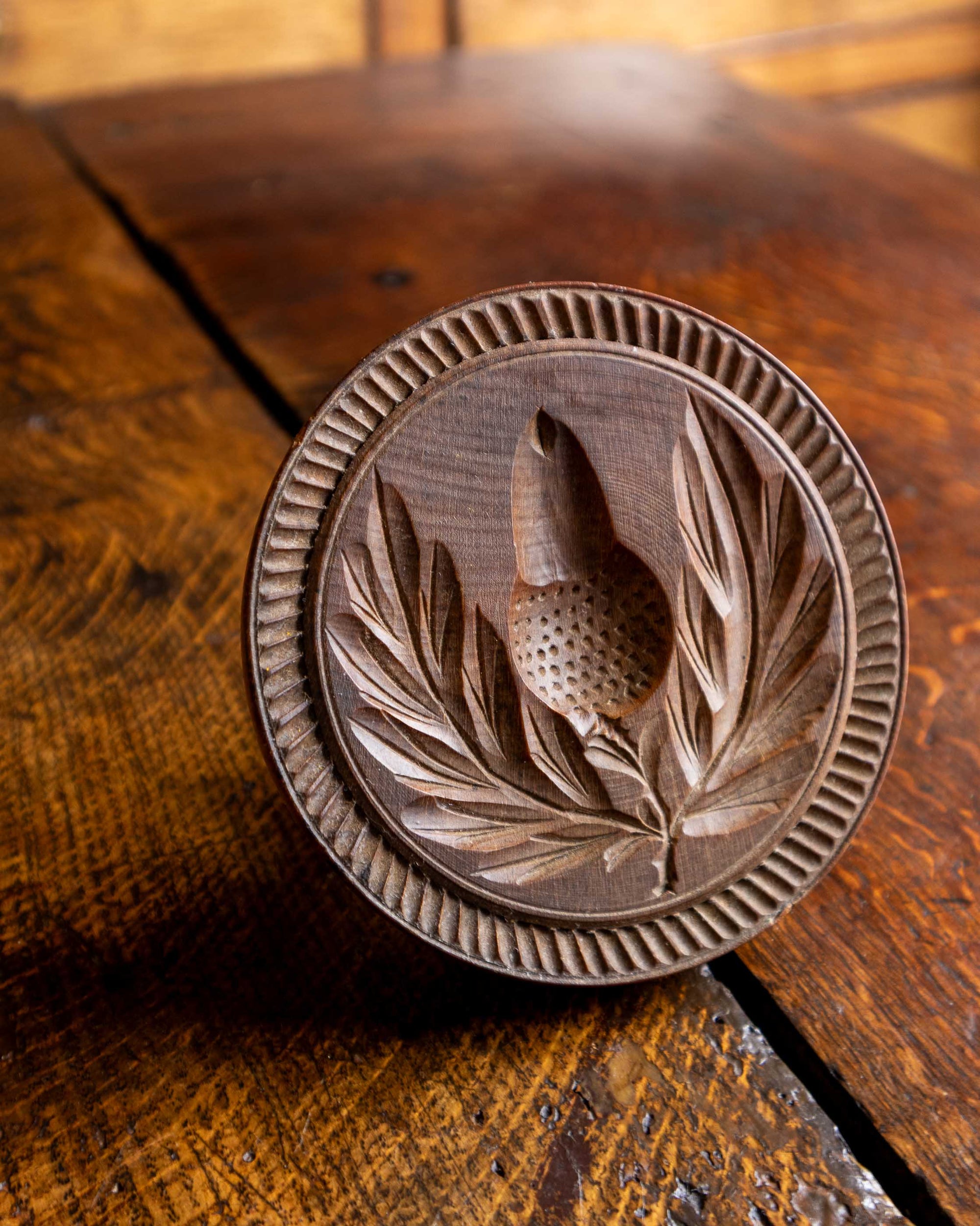 Wooden butter stamp with leaf and acorn design on a wooden surface