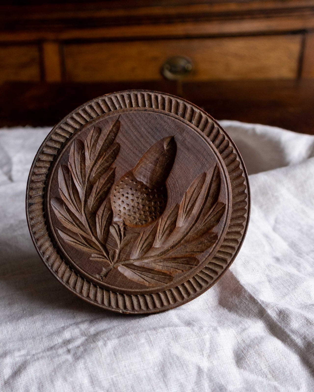 Wooden butter stamp with leaf and acorn design on a white cloth background
