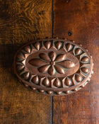 Top of a decorative copper mould on a wooden surface