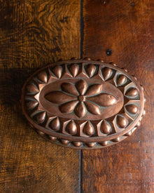 Top of a decorative copper mould on a wooden surface