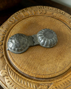 Decorative wooden breadboard with a pewter mould on a dark background