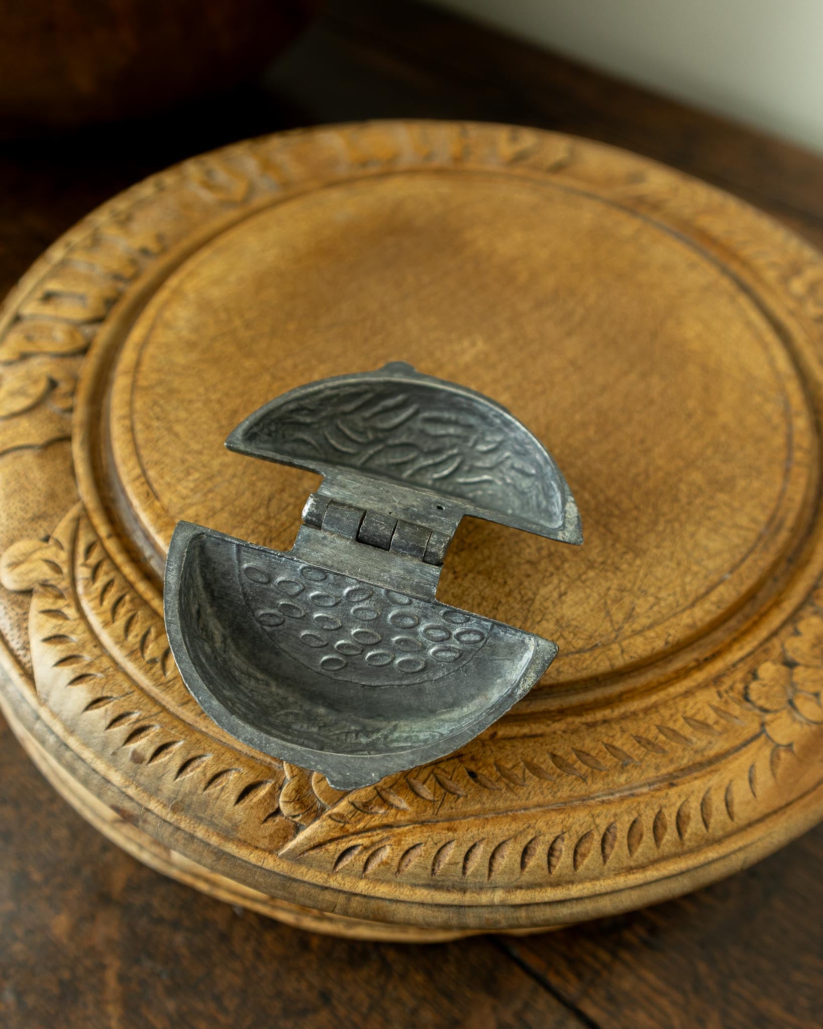 Decorative wooden breadboard with a pewter mould on a dark background