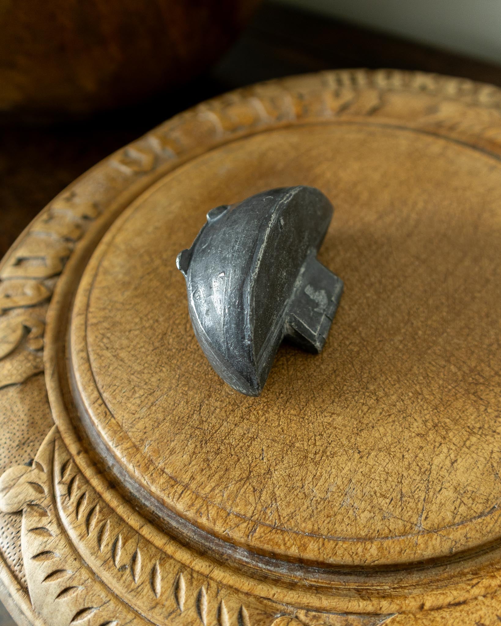 Decorative wooden breadboard with a pewter mould on a dark background