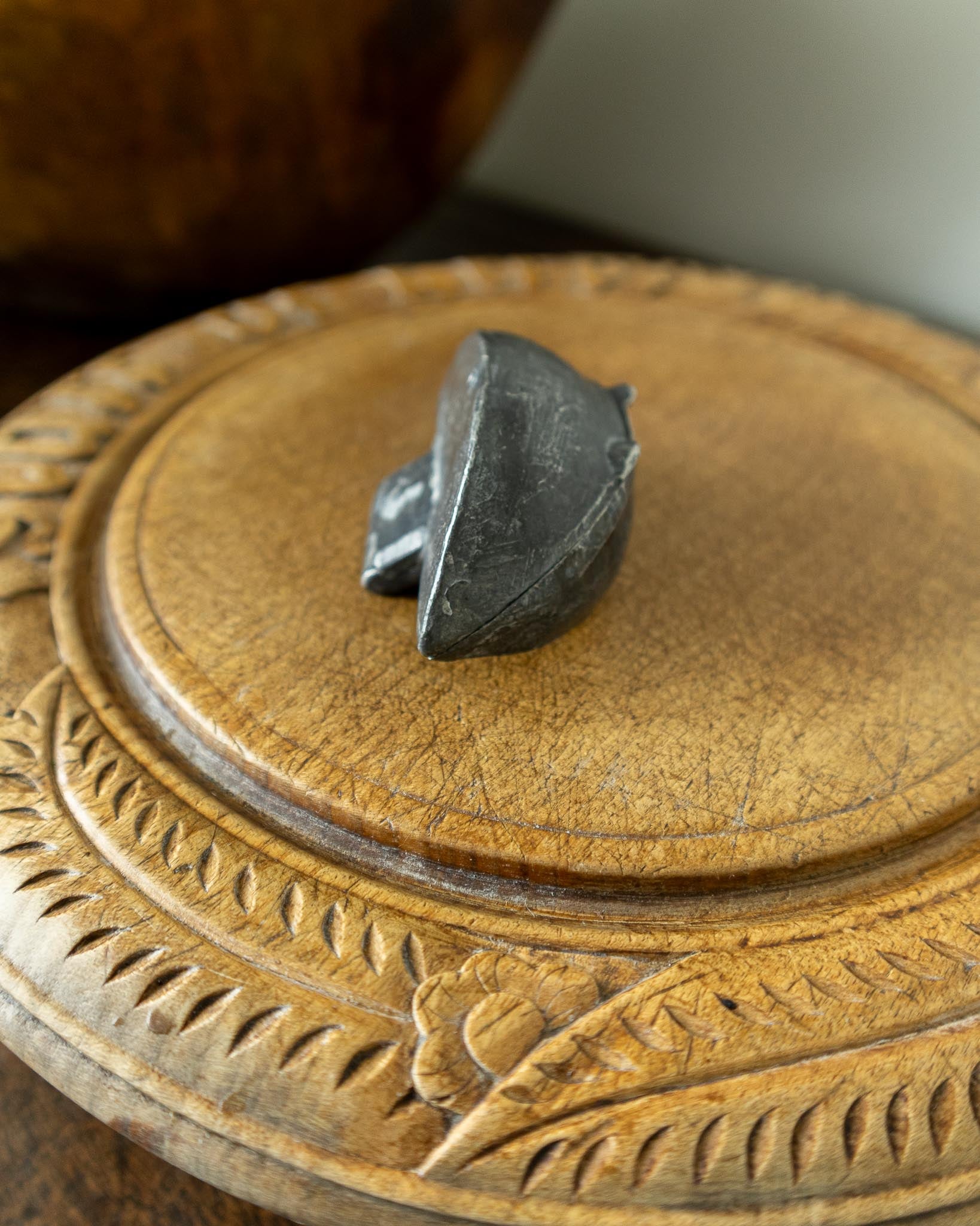 Decorative wooden breadboard with a pewter mould on a dark background