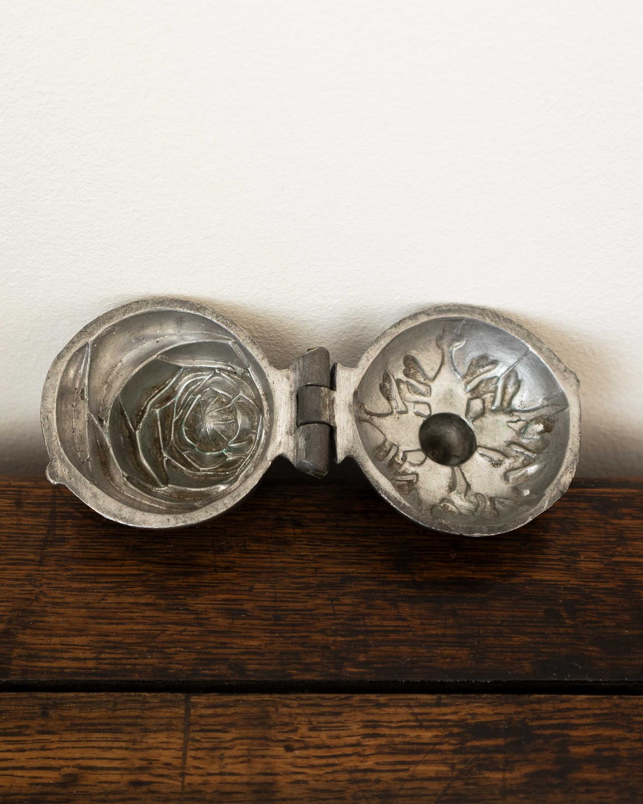 Pewter mould with intricate designs on a wooden surface