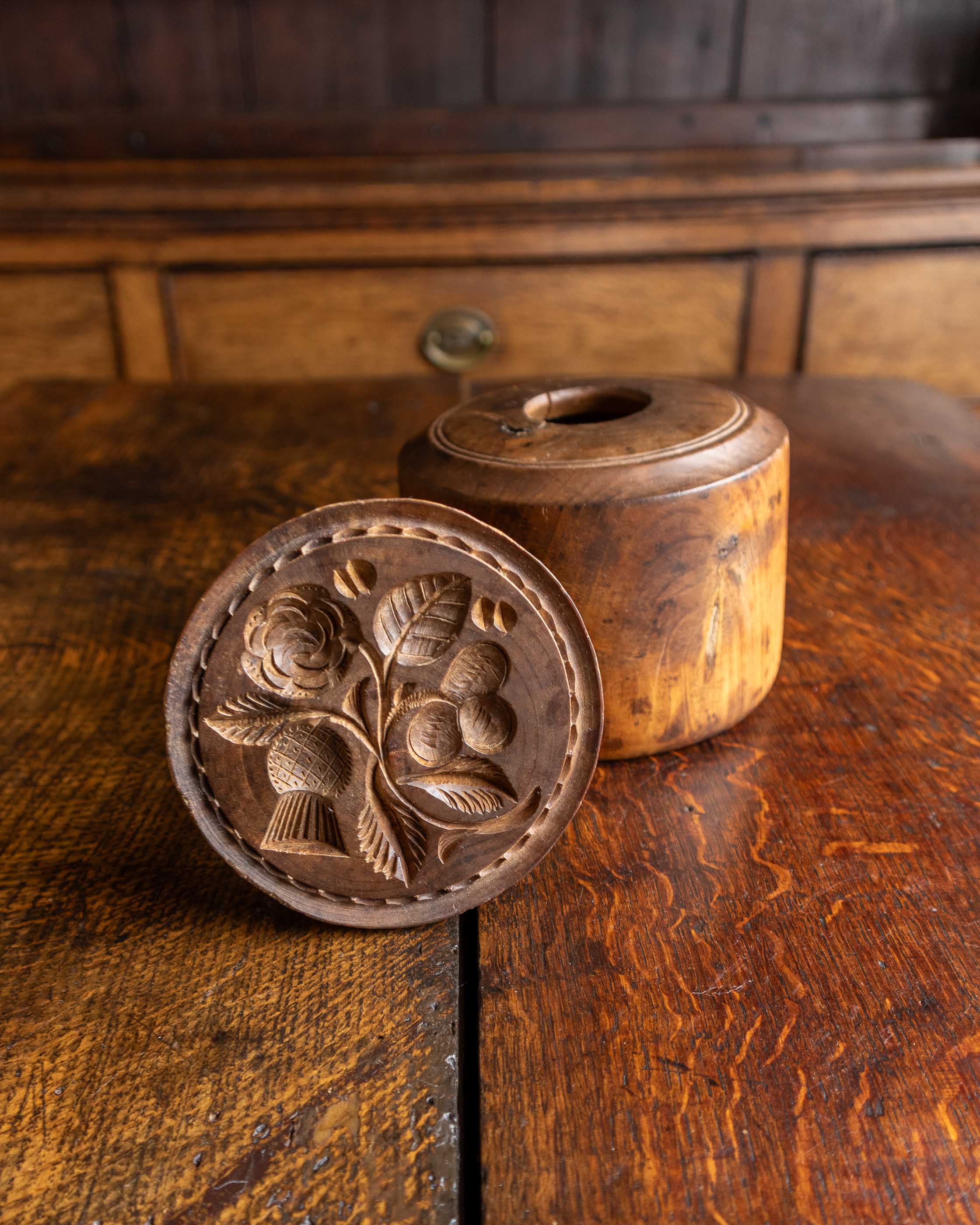 Wooden butter stamp with floral design on a wooden surface