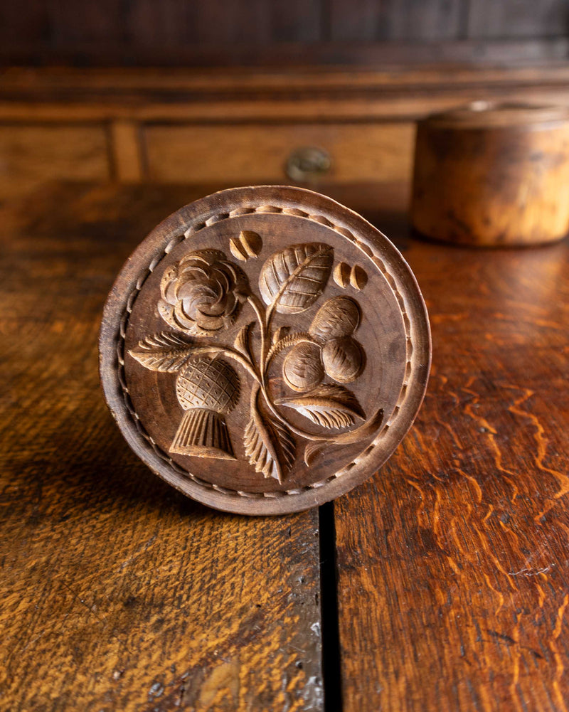 Wooden butter stamp with floral design on a wooden surface
