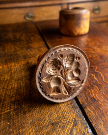 Decorative wooden butter stamp with floral design on a wooden surface