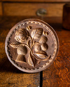 Wooden butter stamp with floral design on a wooden surface