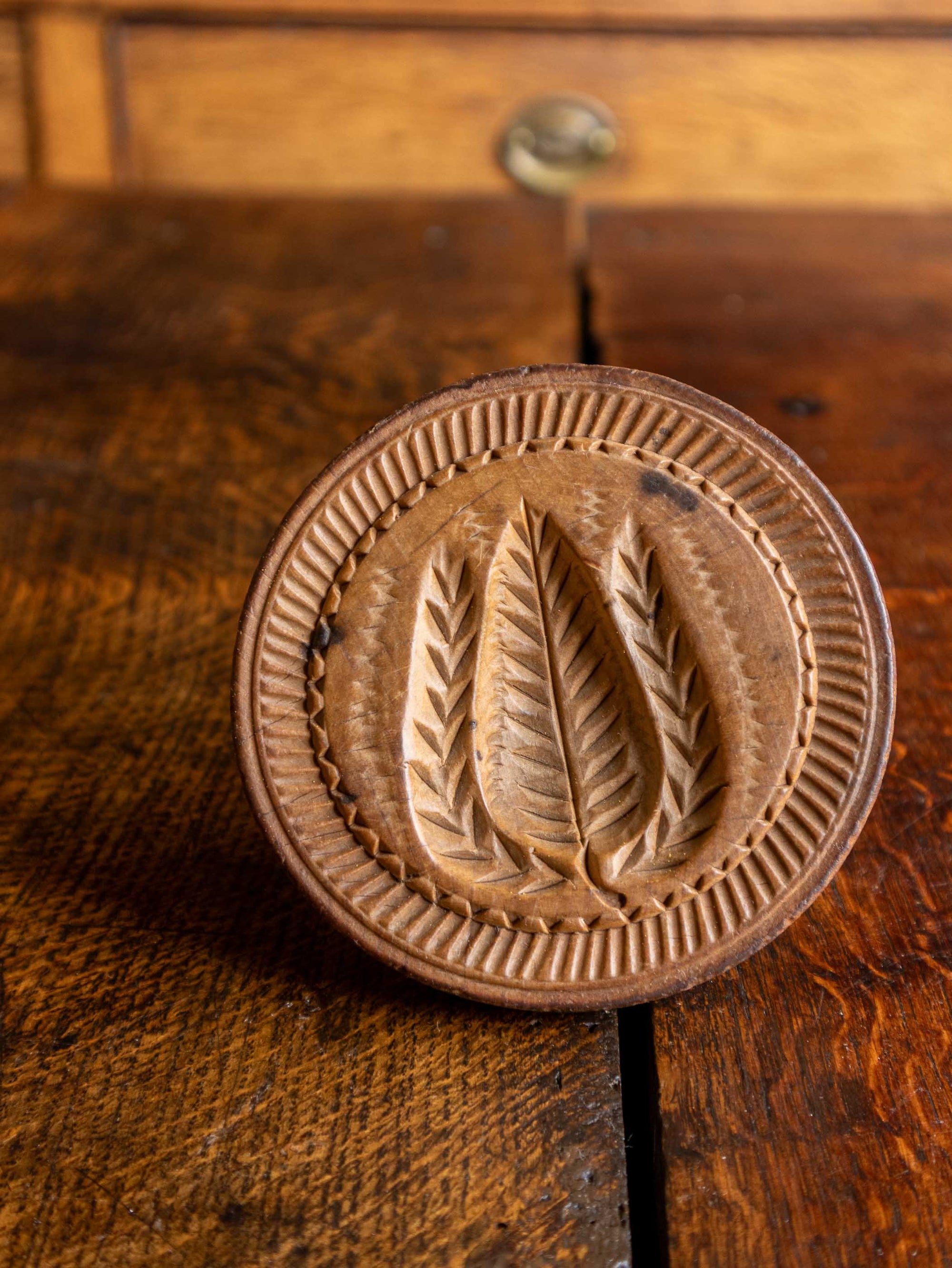 Wooden butter stamp with leaf design on a wooden surface
