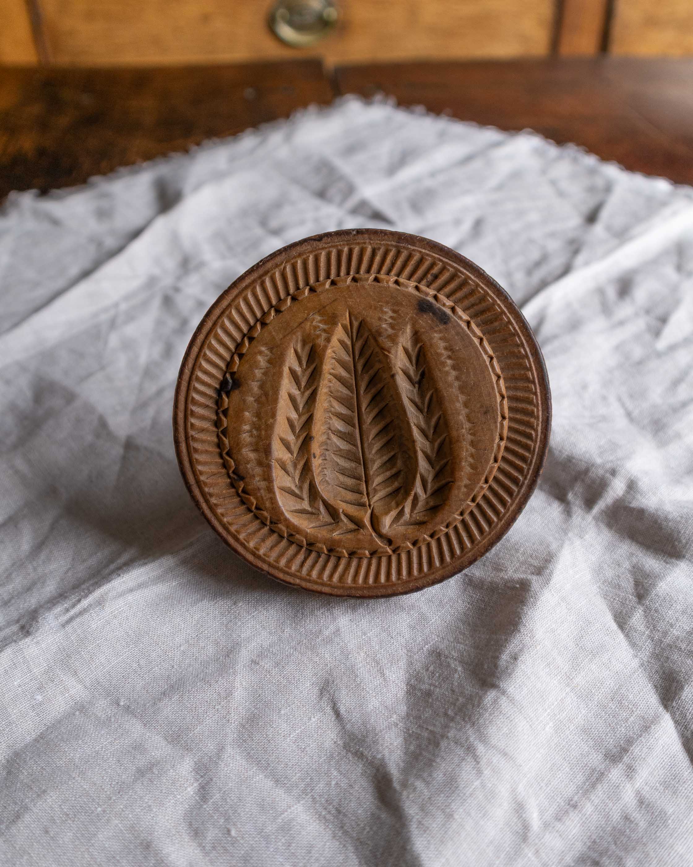 Wooden butter stamp with leaf design on a white cloth