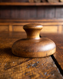 Wooden butter stamp handle on a wooden surface with a warm tone