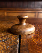 Wooden butter stamp handle on a wooden surface with a blurred background
