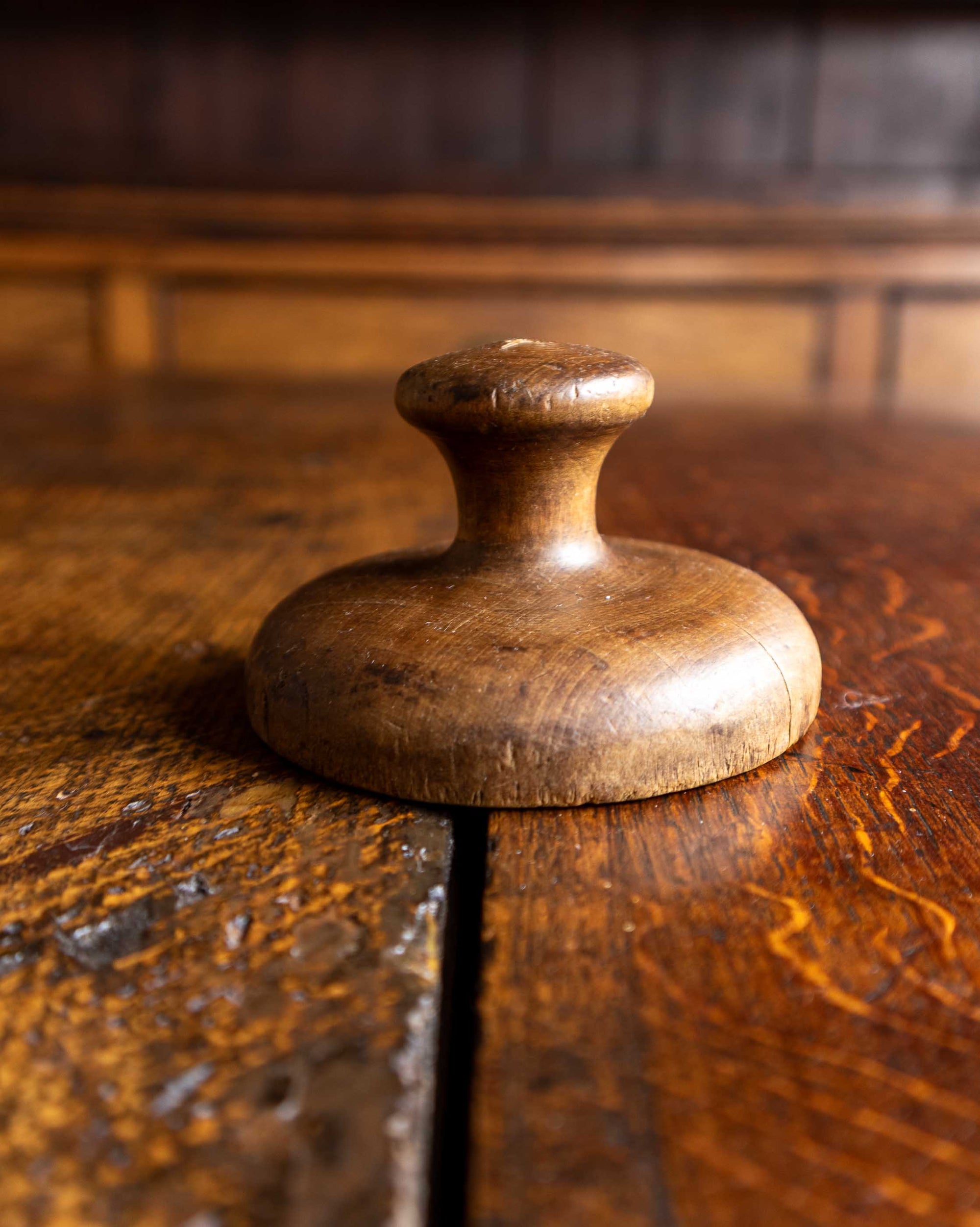 Wooden butter stamp handle on a wooden surface with a blurred background