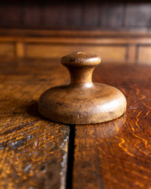 Wooden butter stamp handle on a wooden surface with a blurred background