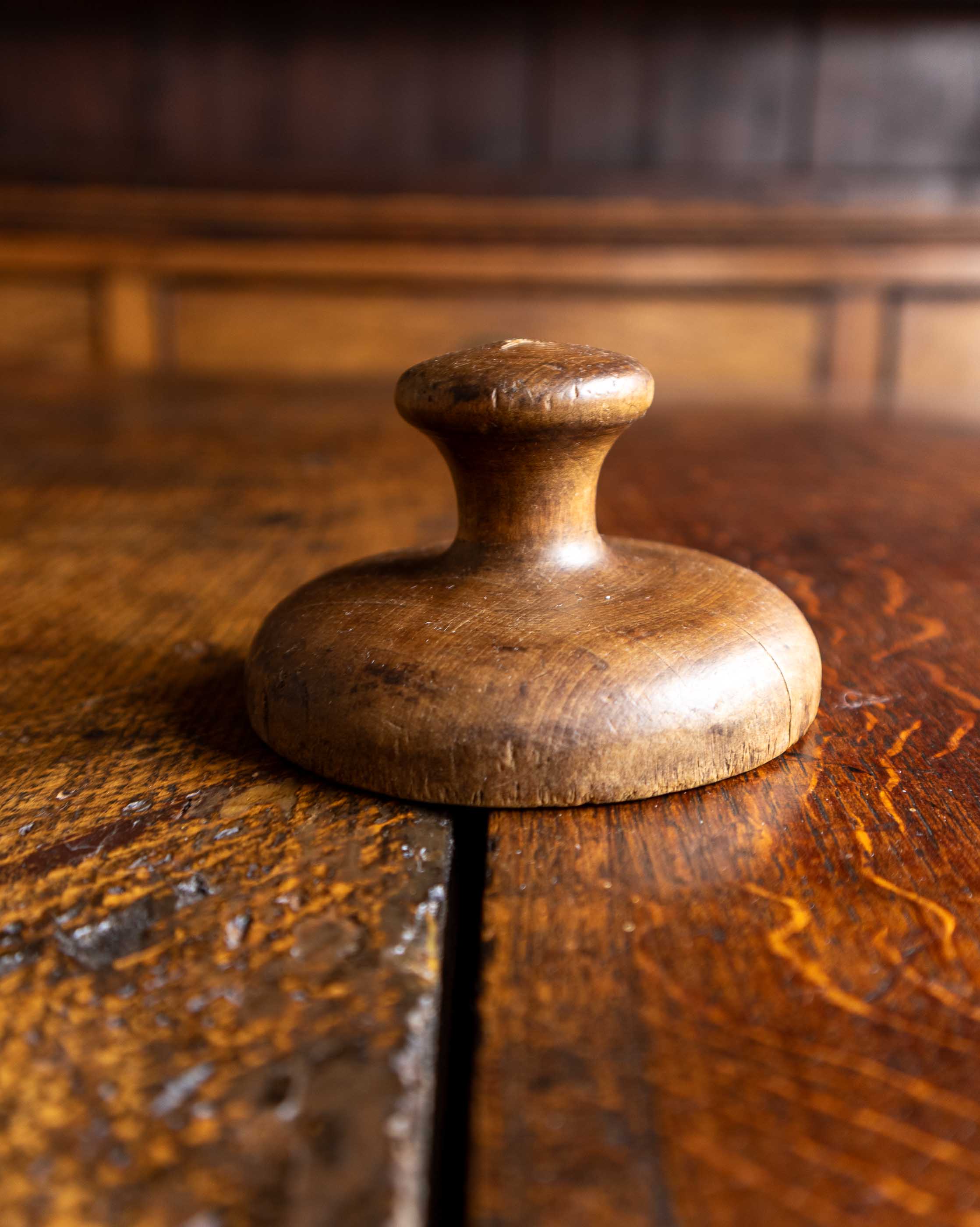 Wooden butter stamp handle on a wooden surface with a blurred background