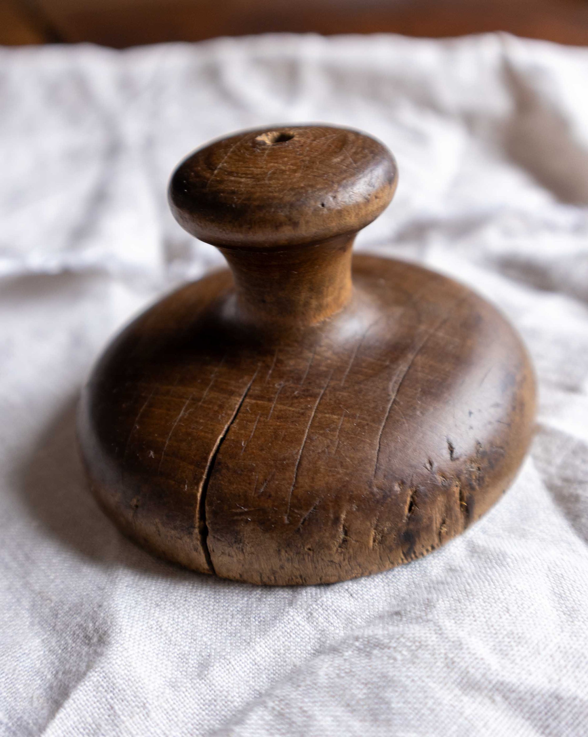 Wooden butter print handle on a textured white fabric background