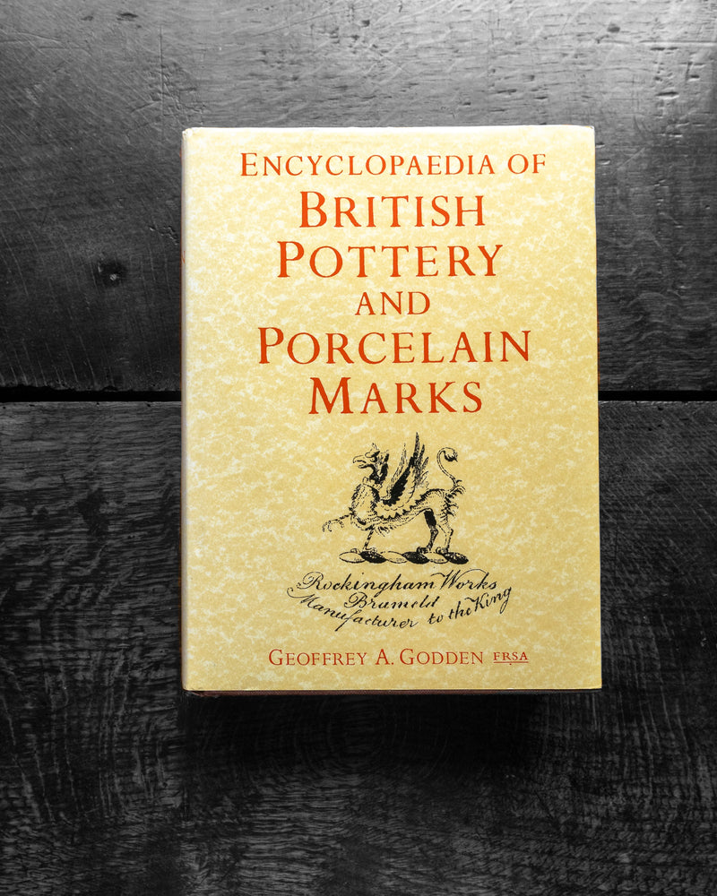 Book titled 'Encyclopaedia of British Pottery and Porcelain Marks' on a dark wooden surface