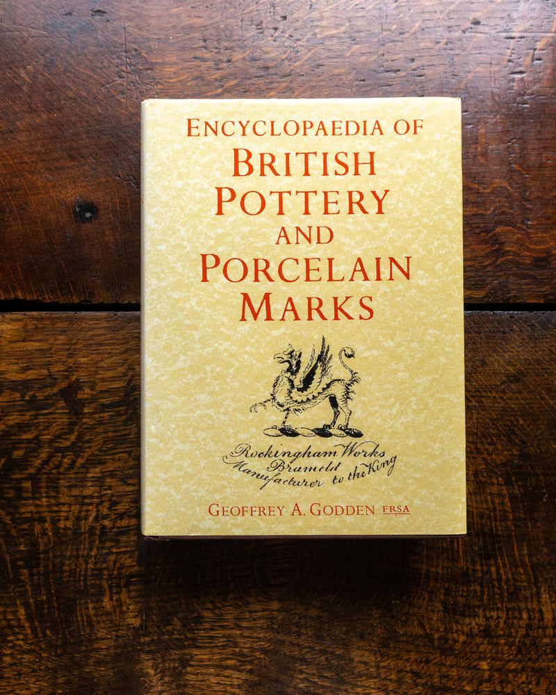 Book titled 'Encyclopaedia of British Pottery and Porcelain Marks' on a wooden surface