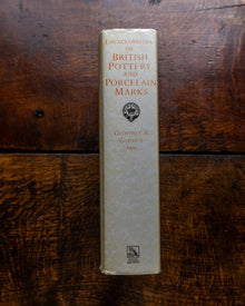 Book titled 'Encyclopedia of British Pottery and Porcelain Marks' on a wooden surface