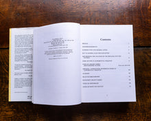 Open book on a wooden surface with a table of contents visible