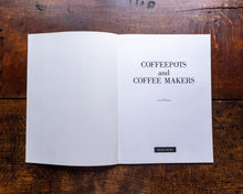 Open book on a wooden surface with text 'COFFEEPOTS and COFFEE MAKERS'.