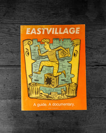 Book cover of 'Eastvillage' with illustration of a person climbing a wall on an orange background