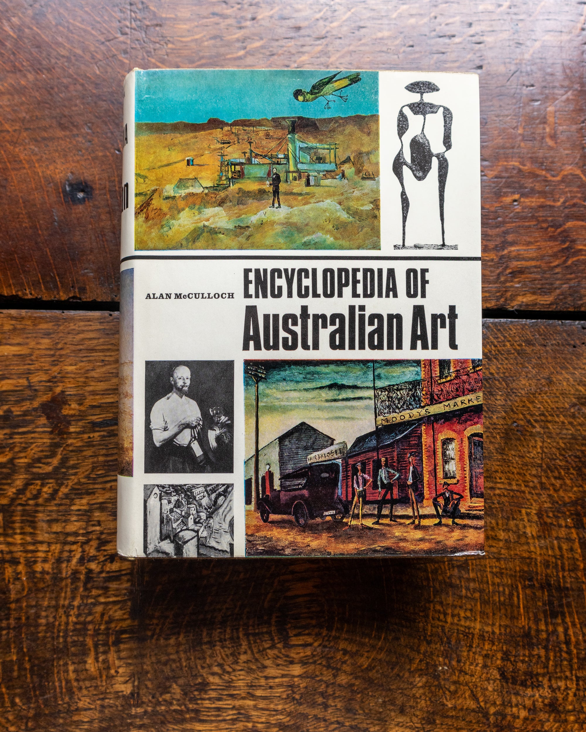 Book titled 'Encyclopedia of Australian Art' on a wooden surface