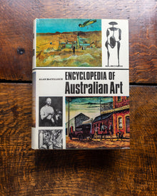 Book titled 'Encyclopedia of Australian Art' on a wooden surface