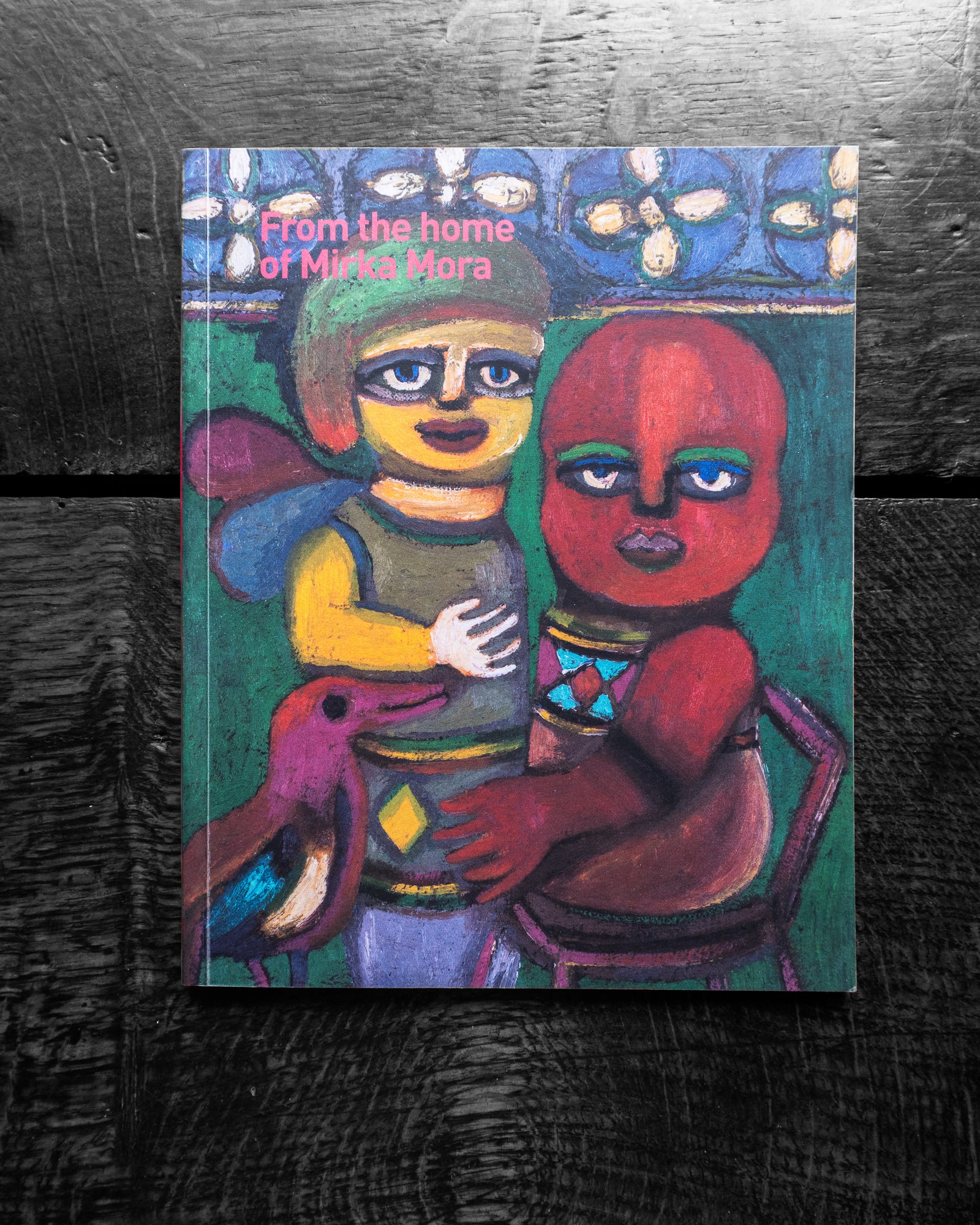 Book cover with colorful painting by Mirka Mora of two figures and a dog on a dark textured background