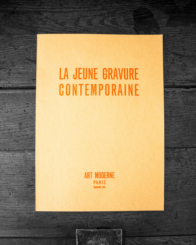 Book cover with text 'LA JEUNE GRAVURE CONTEMPORAINE' on a dark wooden surface