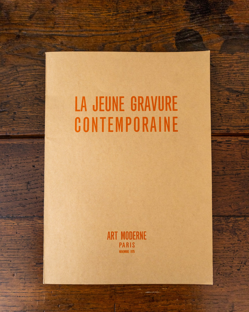 Book cover with text 'LA JEUNE GRAVURE CONTEMPORAINE' on a wooden surface