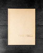 Cover book with embossed text 'The Field' on a dark wooden surface