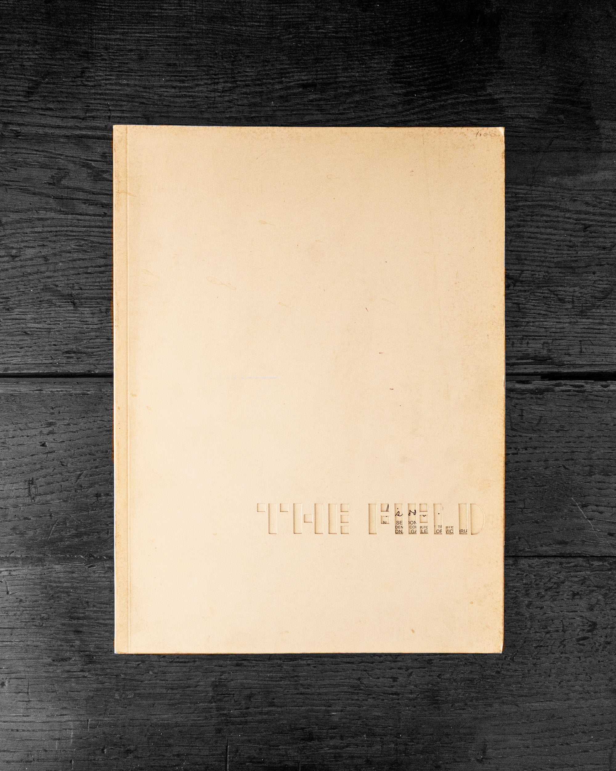 Cover book with embossed text 'The Field' on a dark wooden surface